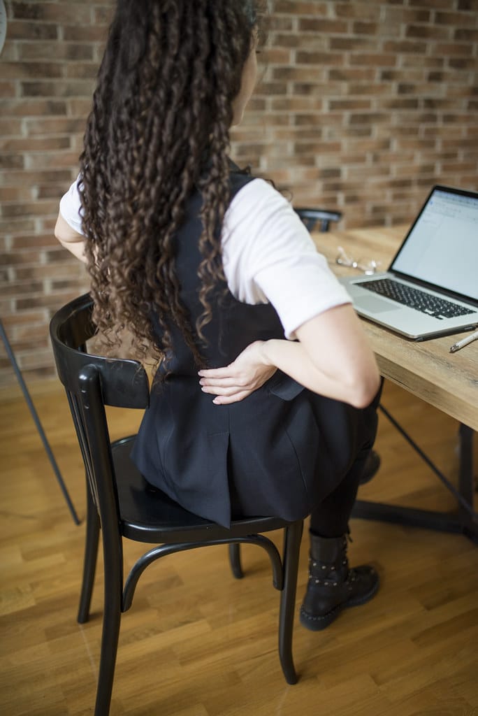 Woman sitting at desk, back view.